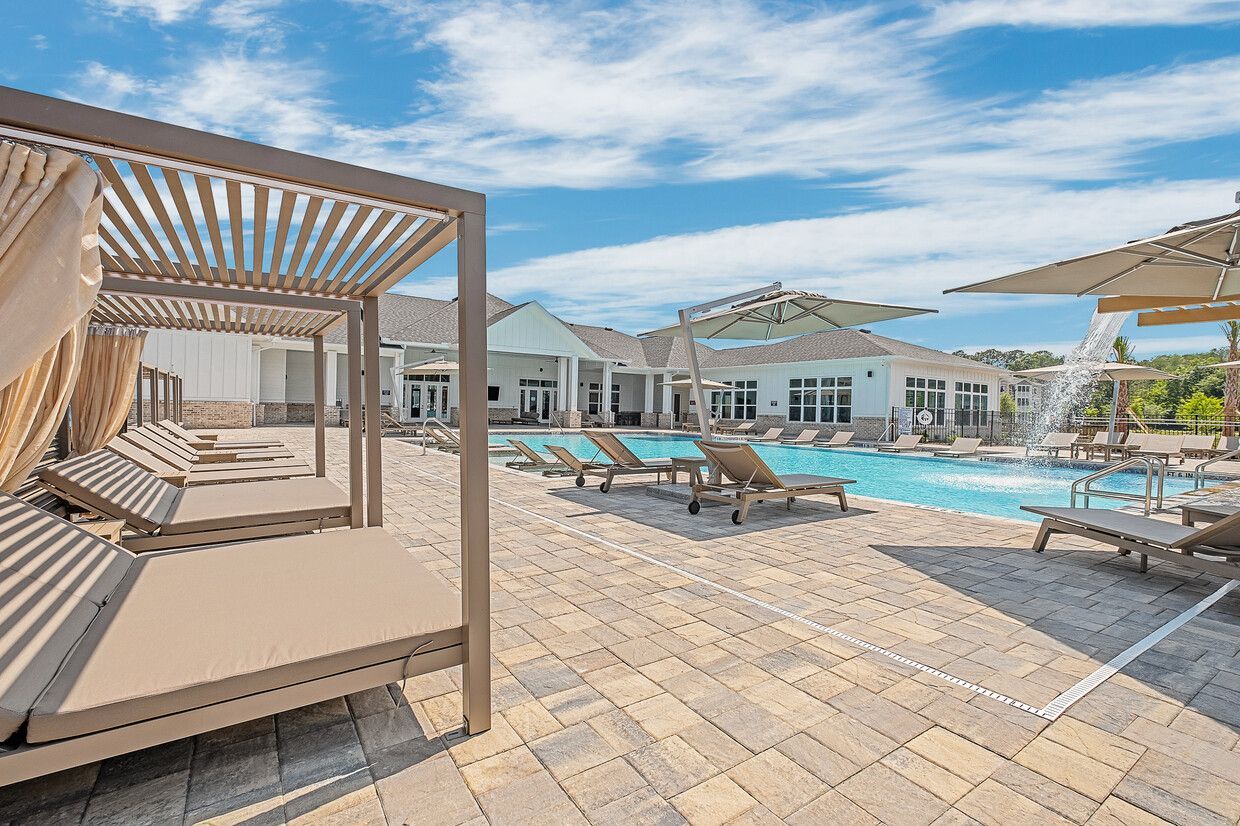 There are a lot of chairs and umbrellas around the pool.