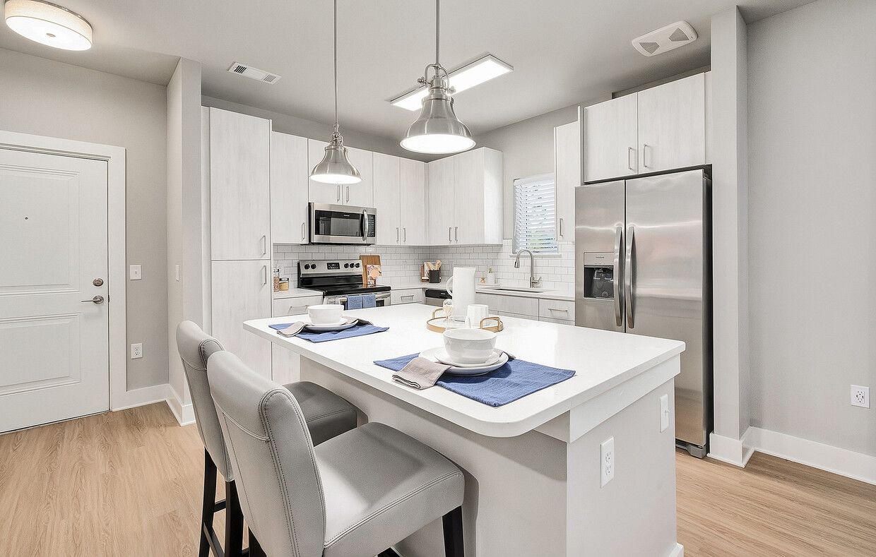 A kitchen with white cabinets , stainless steel appliances , and a large island.