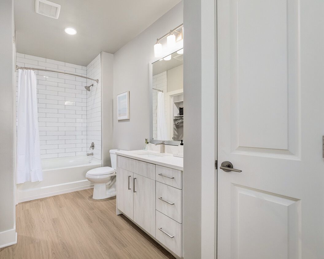A bathroom with a sink , toilet , bathtub and mirror.