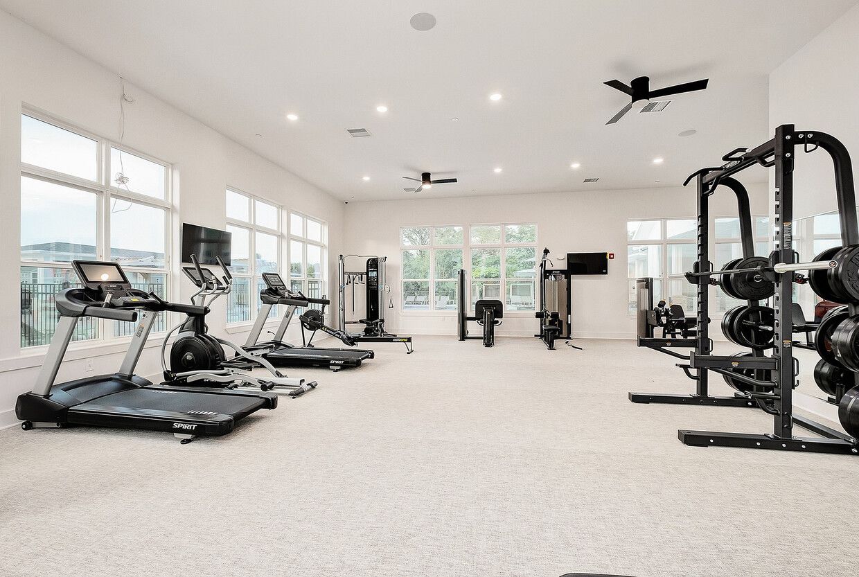 A large gym with treadmills , dumbbells , and a ceiling fan.
