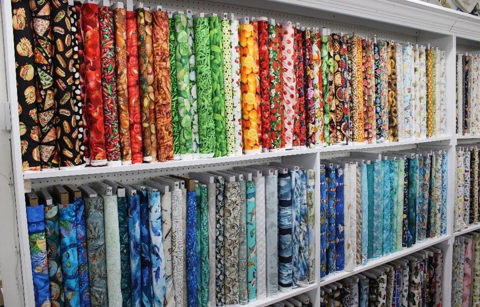 Fabric store shelves stacked with colorful textiles in neat, vibrant rows.