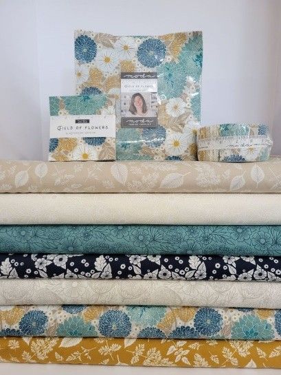 Various quilts with blue, gray, black, and yellow tones and flowers, from a local quilt shop.