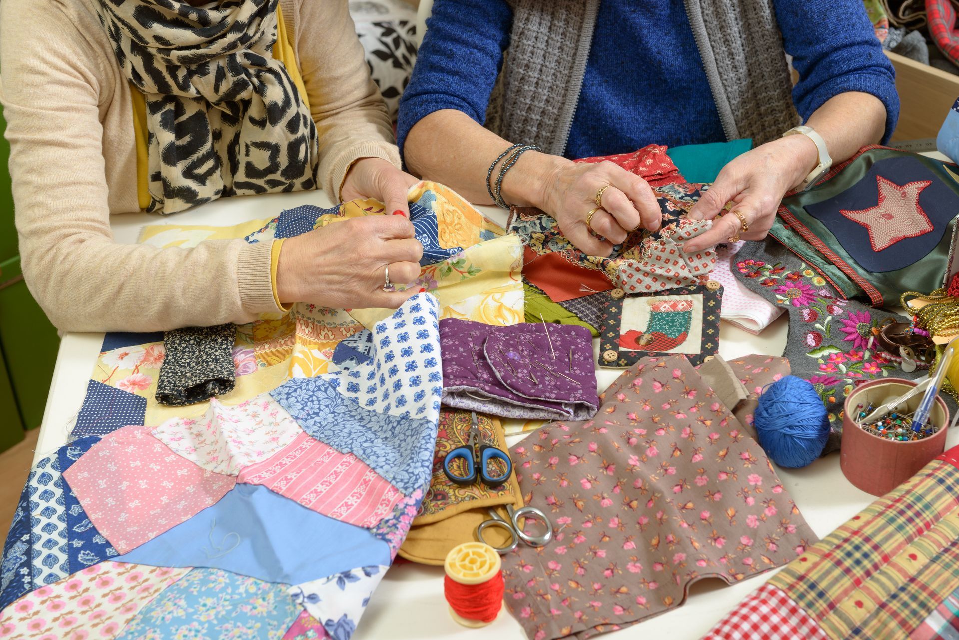 Two women are working on their quilting, using fabrics from a supplier.