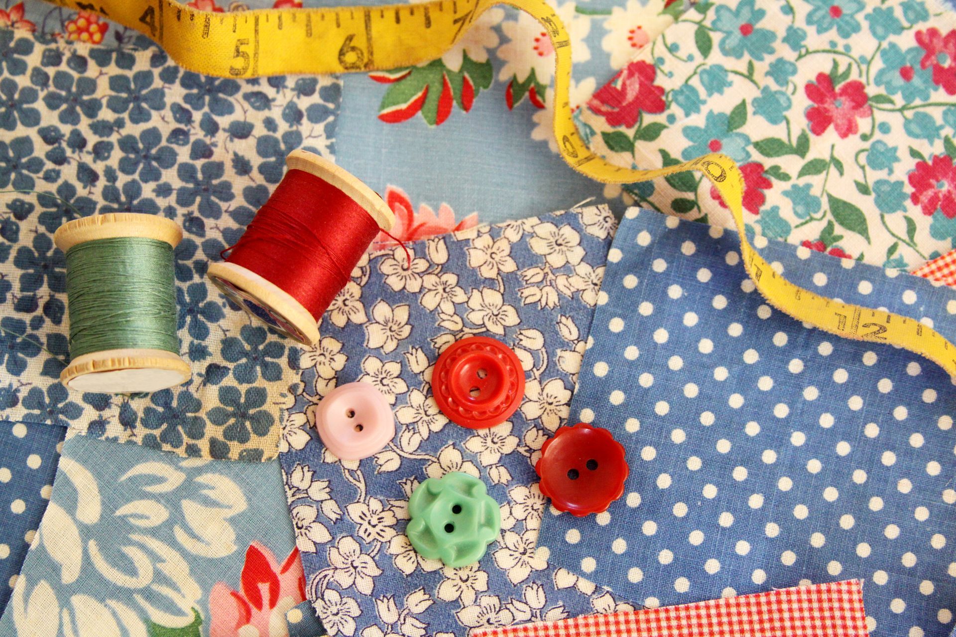 Colorful threads, buttons, and tape laid out on patterned fabric.
