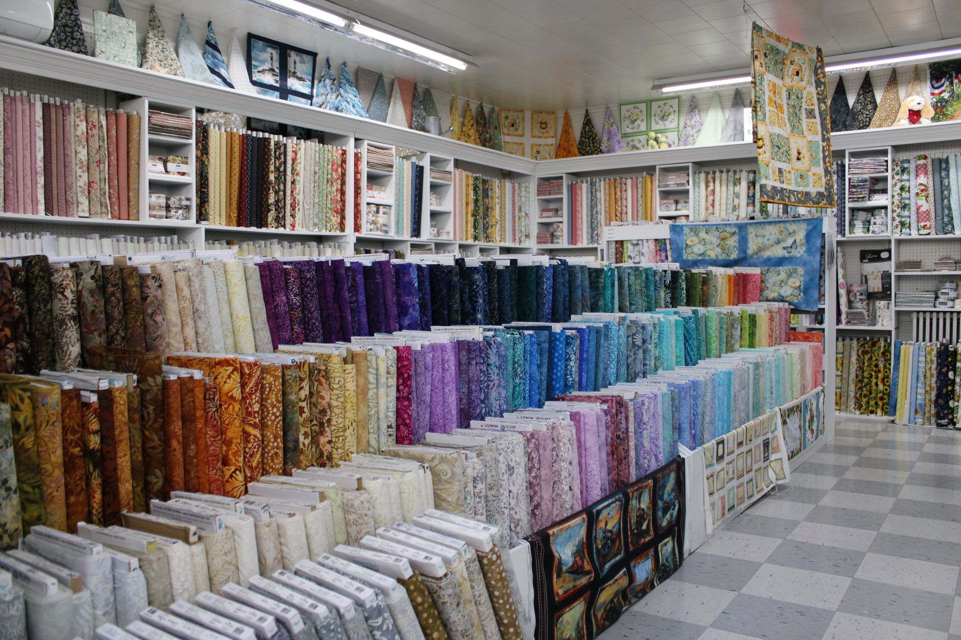 A man touches the bedspreads hanging on a rail in the store.
