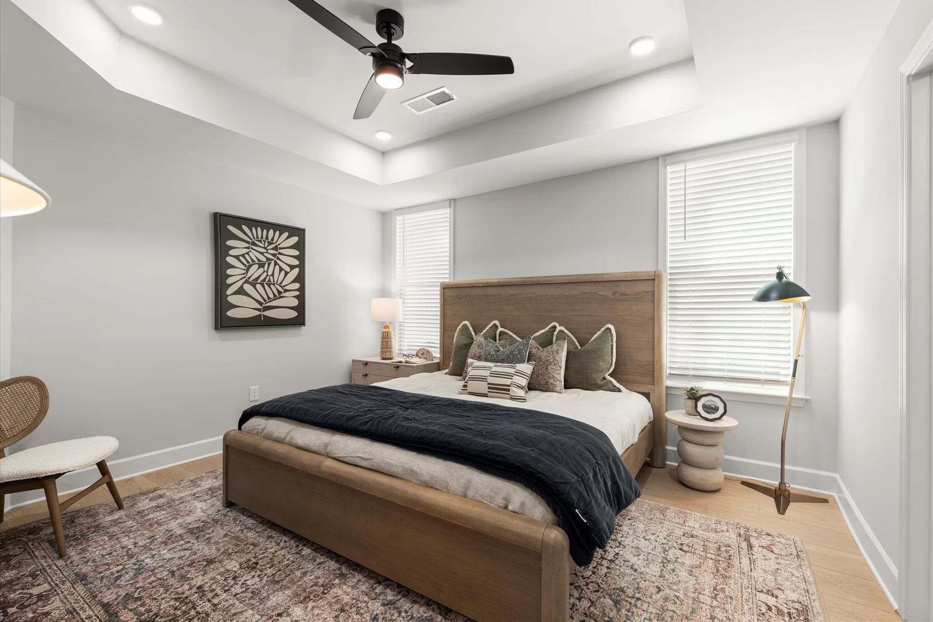 Bedroom with a wooden bed, area rug, and accent pillows. A ceiling fan hangs above.