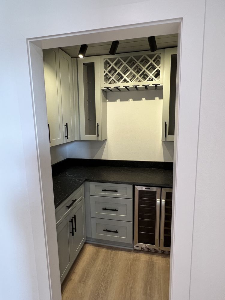 Small built-in closet with gray cabinets, black countertop, wine rack, and wood flooring