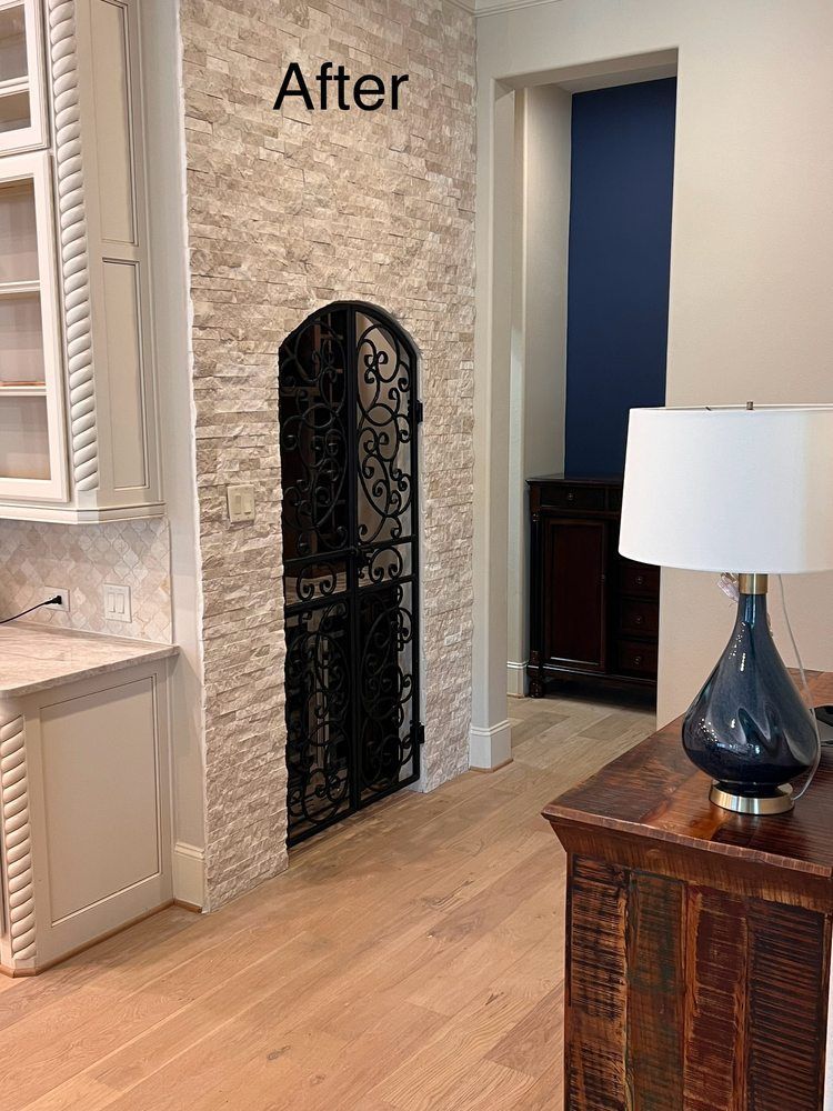 After photo of a living room with a stone fireplace surround and black fireplace screen.