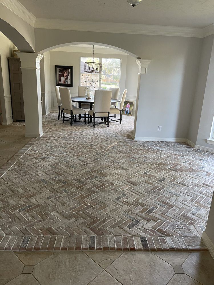 Empty living room with patterned carpet, arched entryways, and dining table by a window.