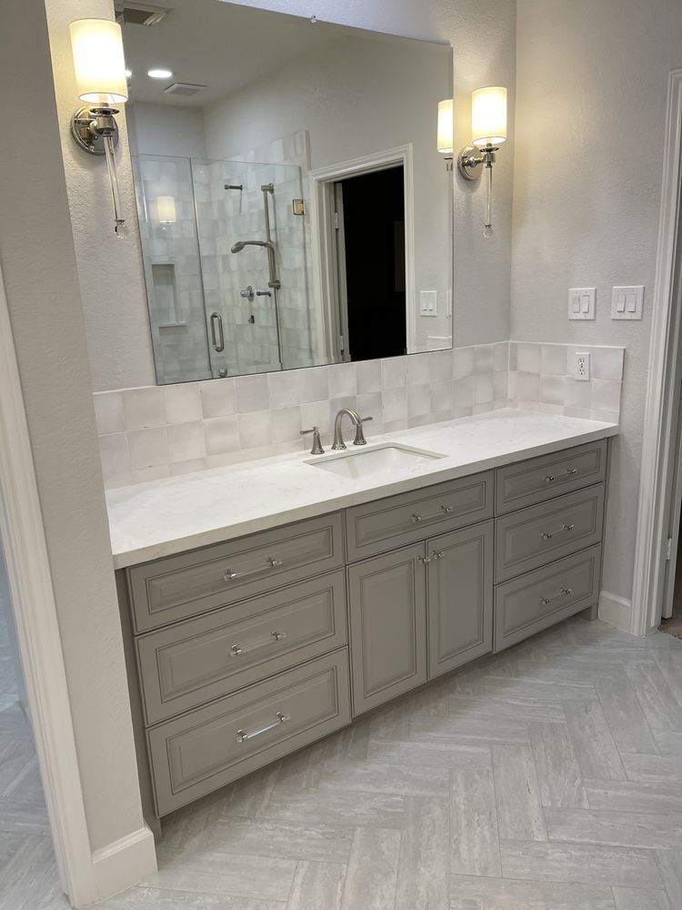 Elegant bathroom vanity with gray cabinets, white countertop, mirrors, and wall sconces