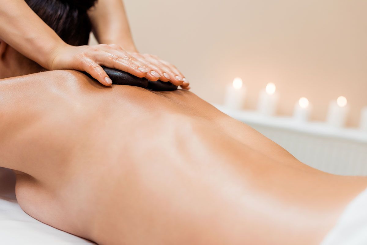 A woman is getting a hot stone massage on her back.
