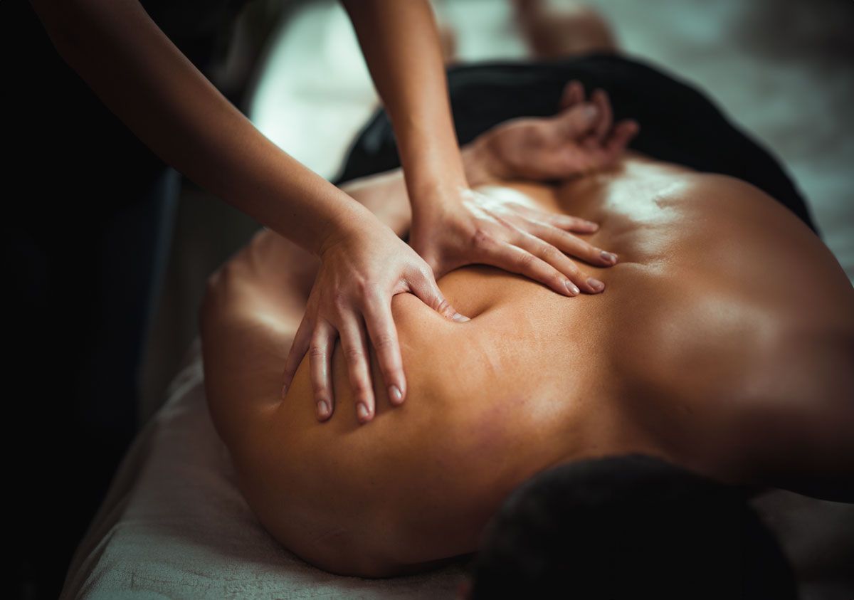 A woman is laying on a bed getting a massage.