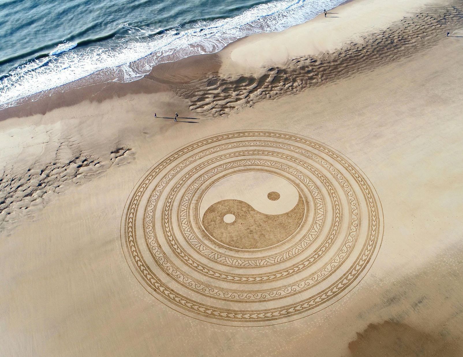 Classical Feng Shui. contact us A yin yang symbol is drawn in the sand on the beach.