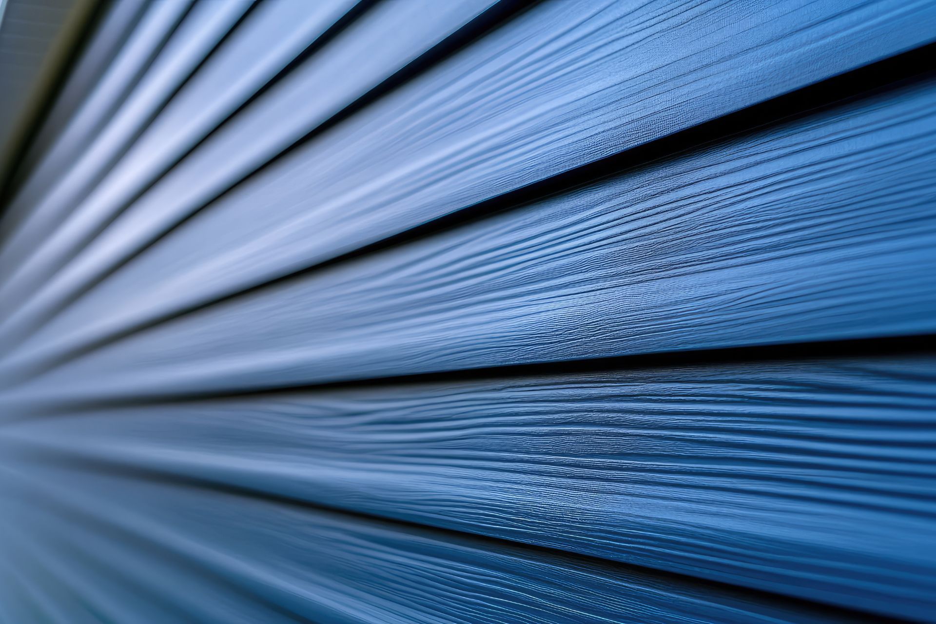 A close-up, angled view of dark blue horizontal siding with a wood-grain texture.