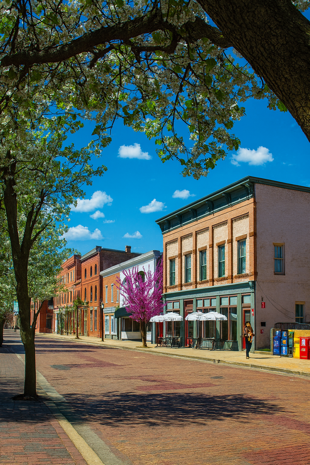 Photo of a city street with vibrant, older buildings across the street and plenty of storefronts