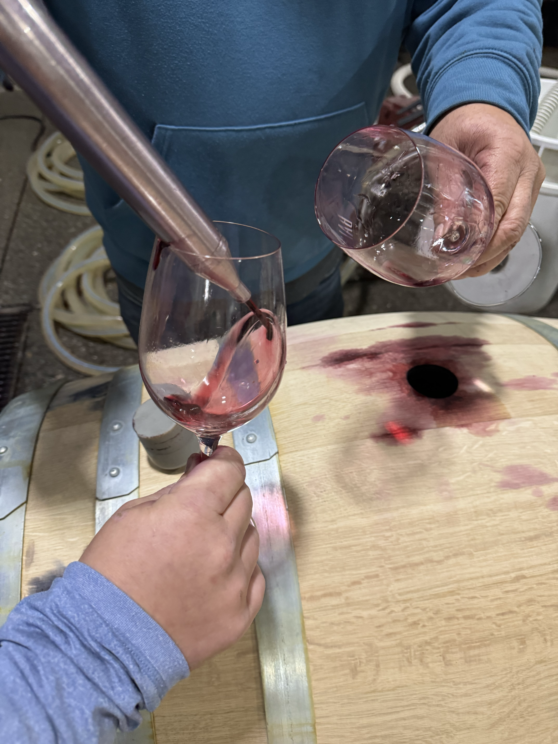 A person is pouring wine into a glass from a barrel