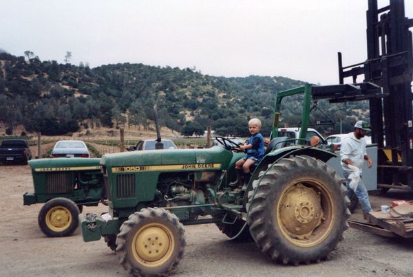A little boy sits on a john deere tractor