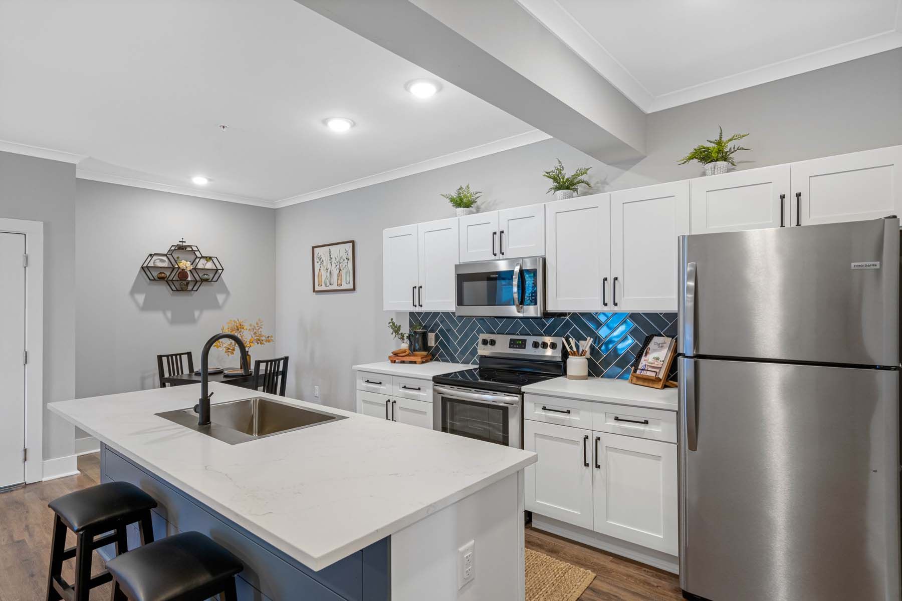 A kitchen with white cabinets , stainless steel appliances , a sink , and a refrigerator  at Pointe Grand Spring Hill.