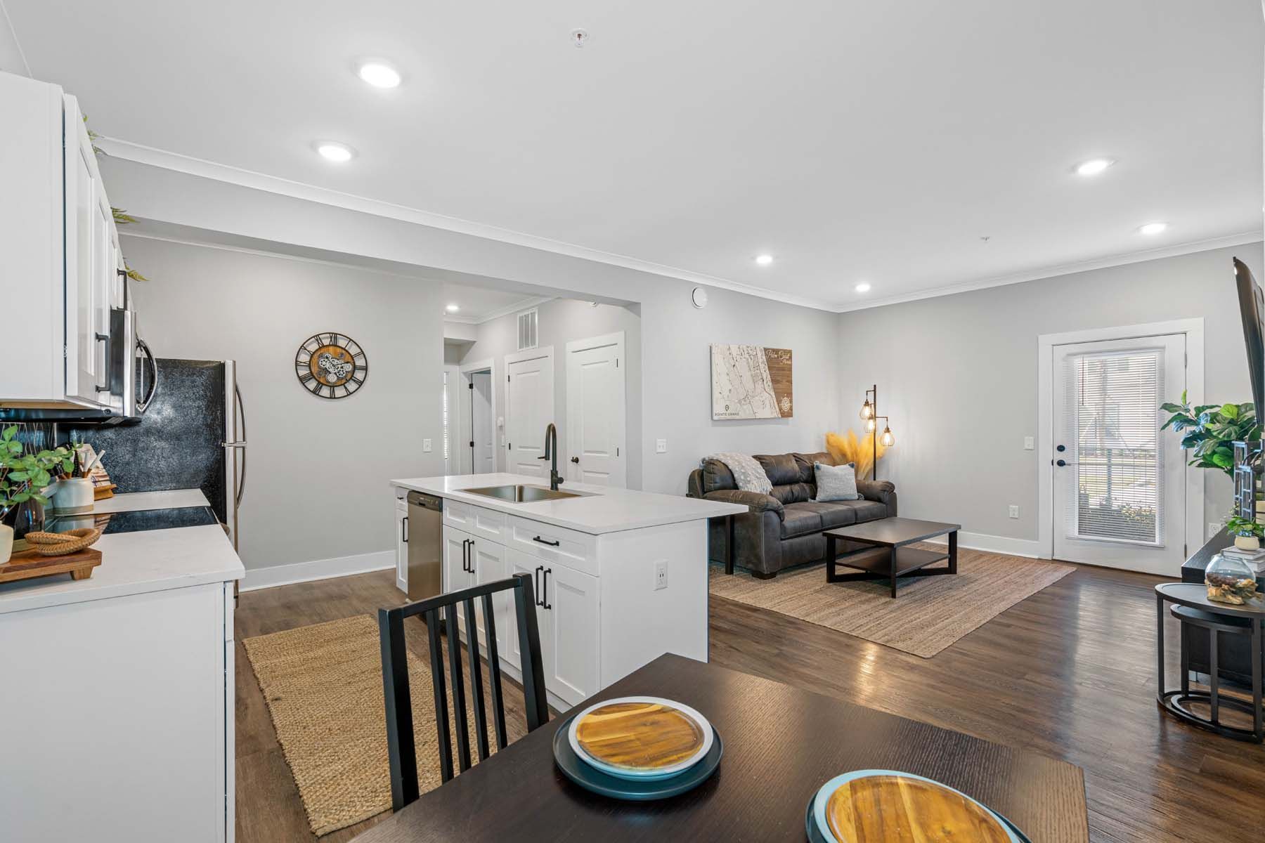 A living room with a couch , table , chairs and a kitchen  at Pointe Grand Spring Hill.