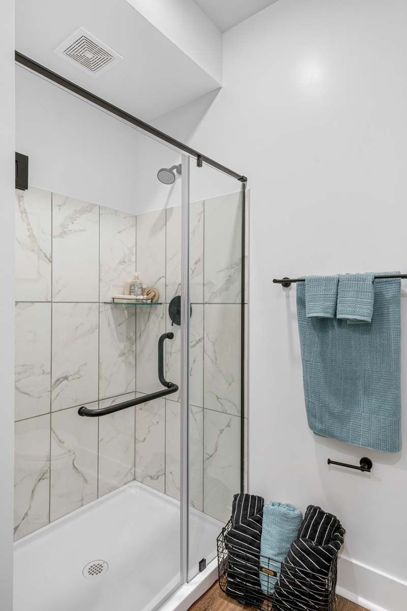 A bathroom with a walk in shower and a towel rack  at Pointe Grand Spring Hill.