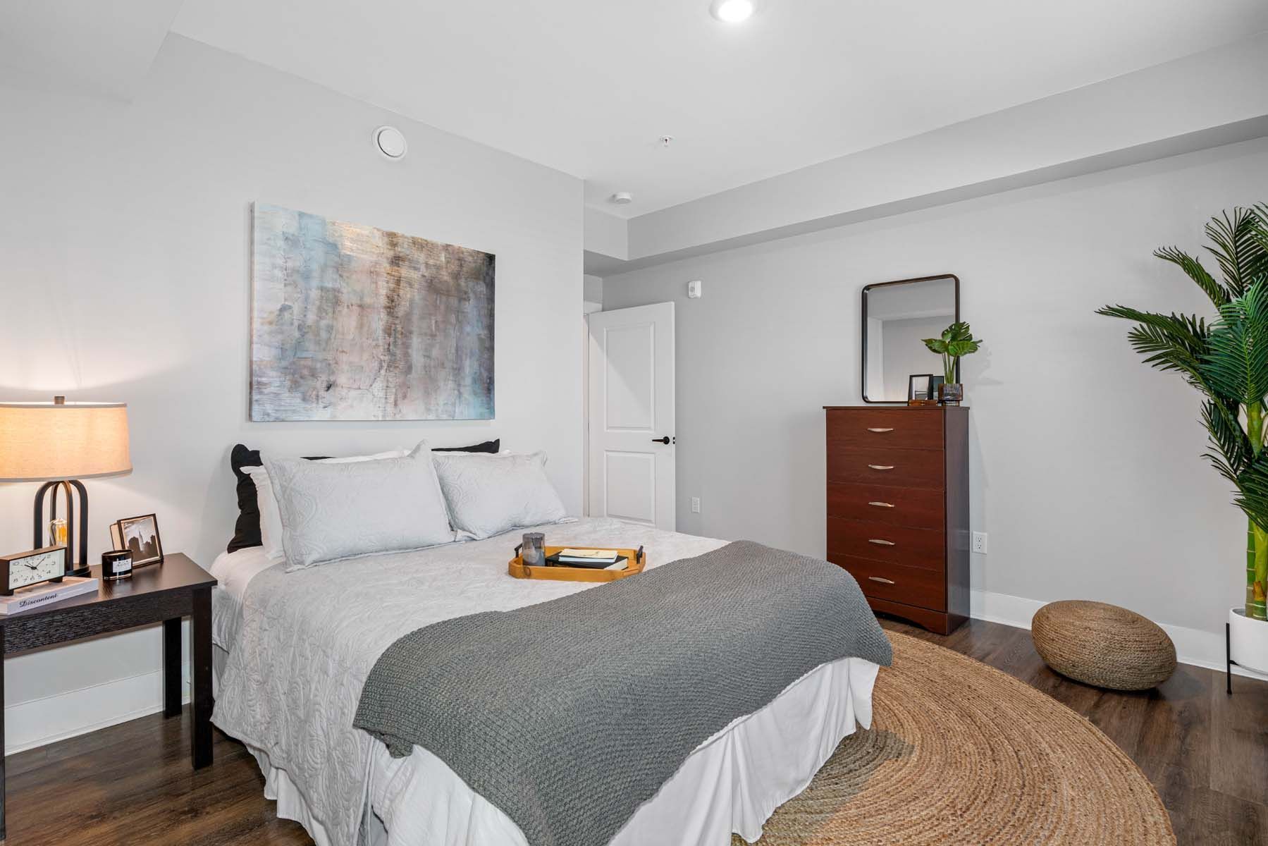 A bedroom with a bed , dresser , lamp and rug  at Pointe Grand Spring Hill.