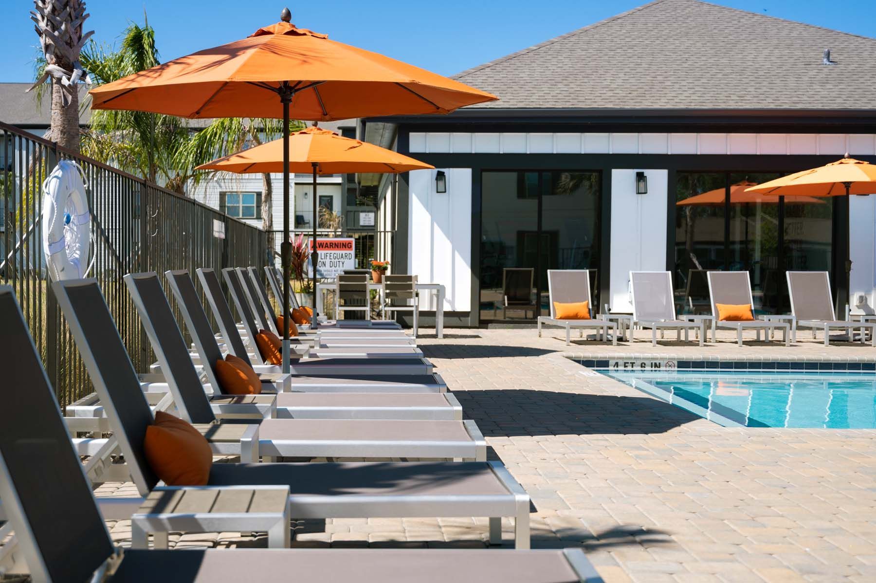 A row of lounge chairs and umbrellas next to a swimming pool  at Pointe Grand Spring Hill.