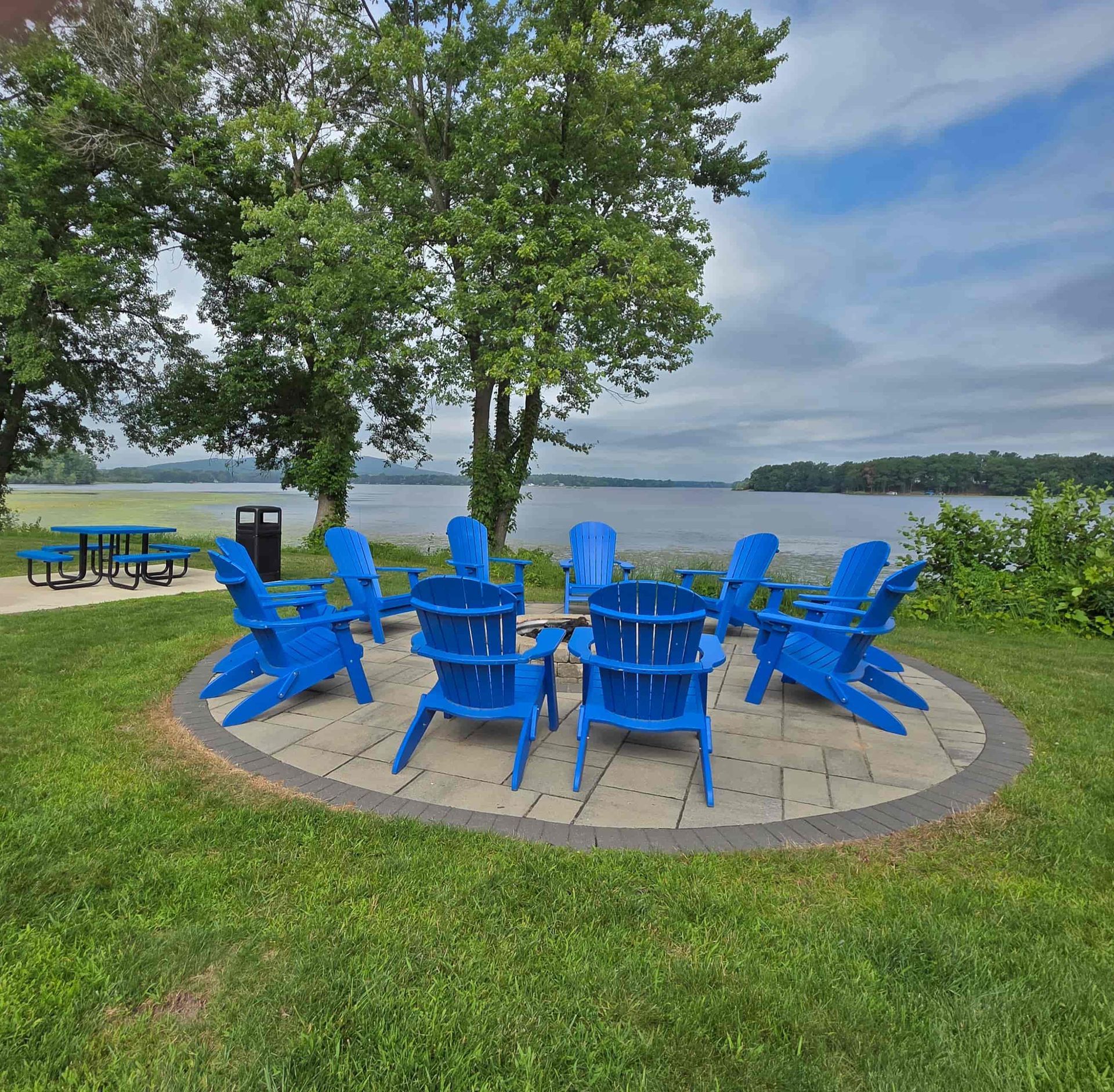 Outdoor fireplace with blue chairs next to the lake