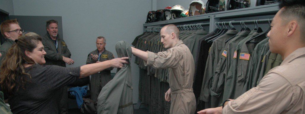 Instructors handing out flight suits to four customers