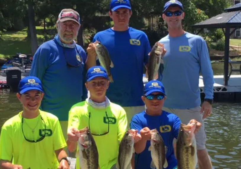 a group of men are standing on a boat holding fish .