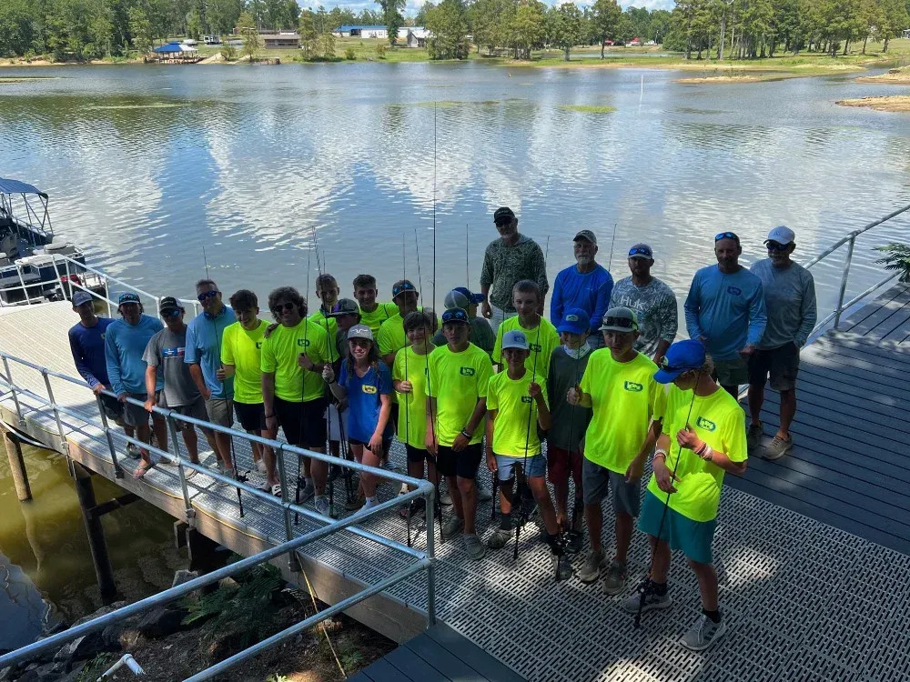 a group of people are standing on a dock next to a lake .