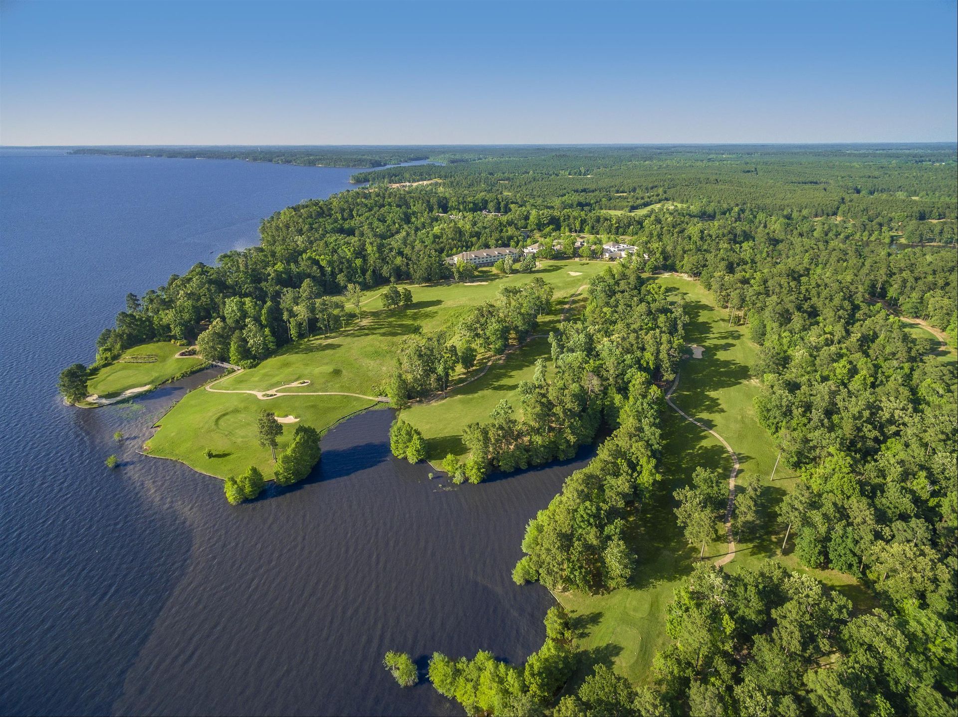 an aerial view of a golf course surrounded by water and trees .