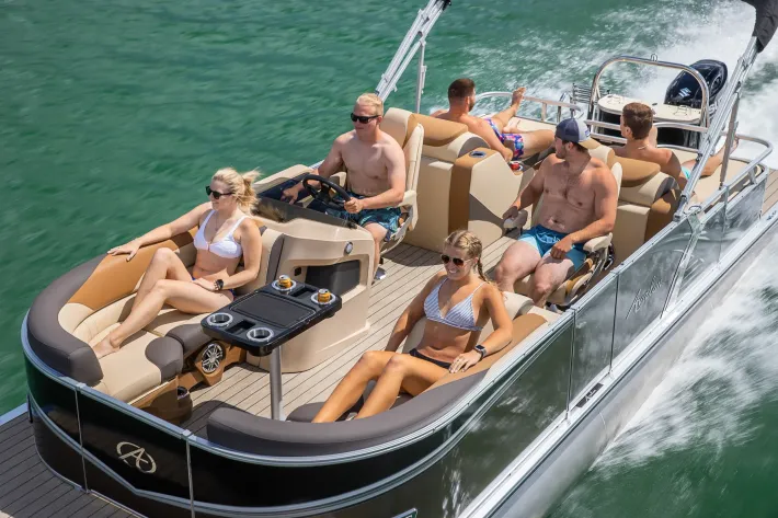 a group of people are sitting on a pontoon boat in the water .