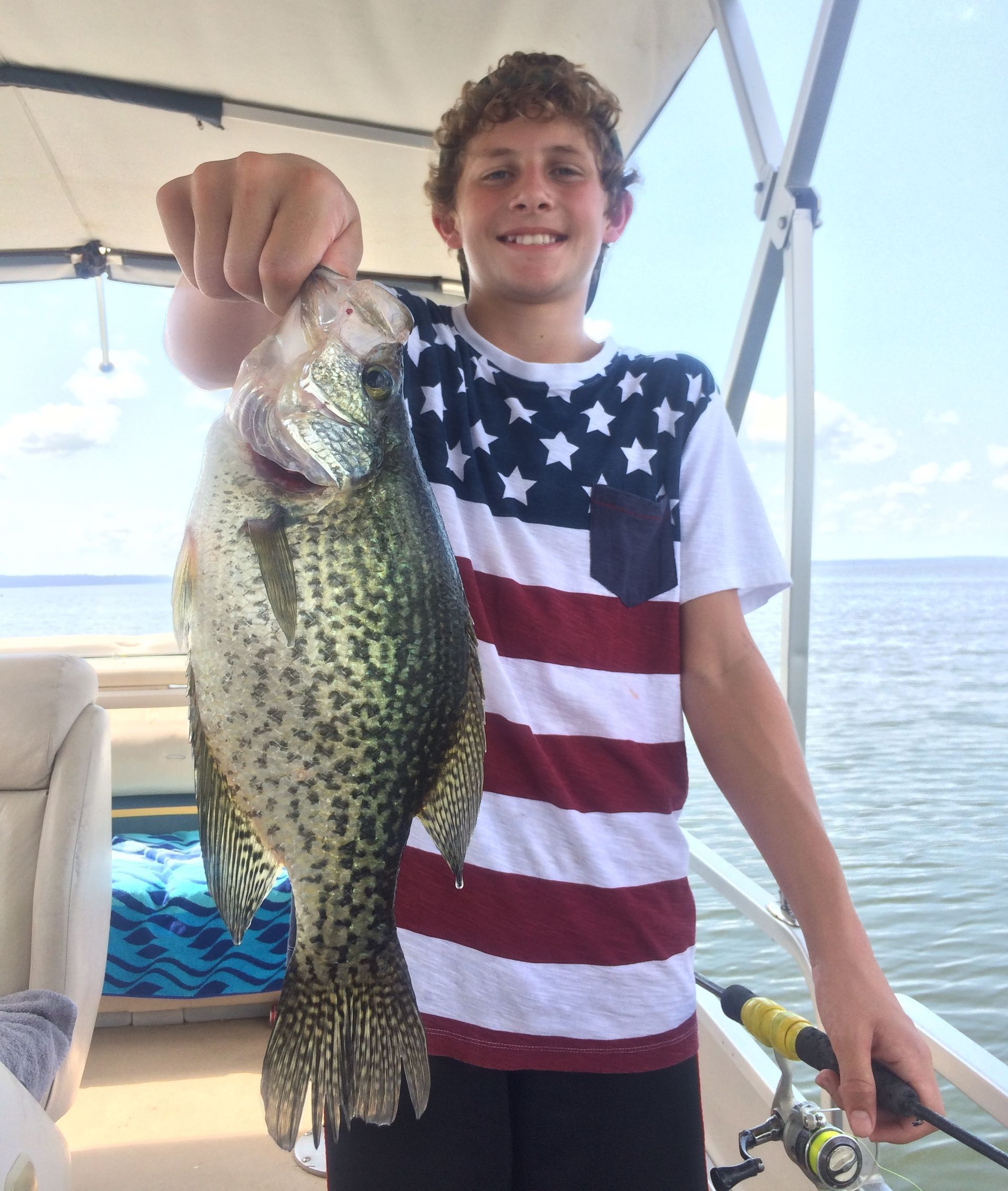 a boy in an american flag shirt is holding a large fish