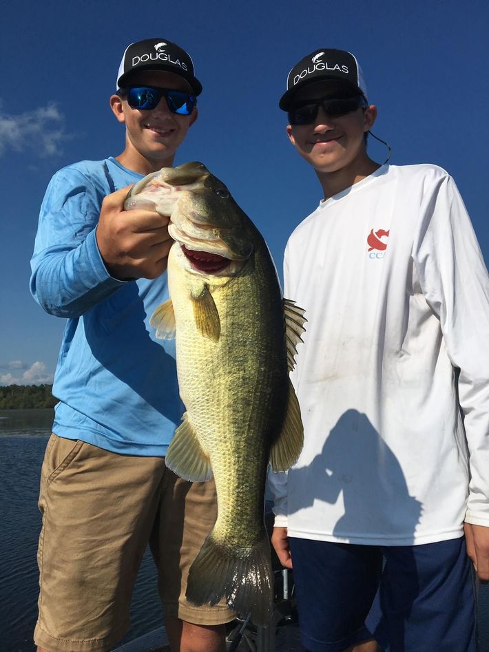 two men standing next to each other holding a large fish
