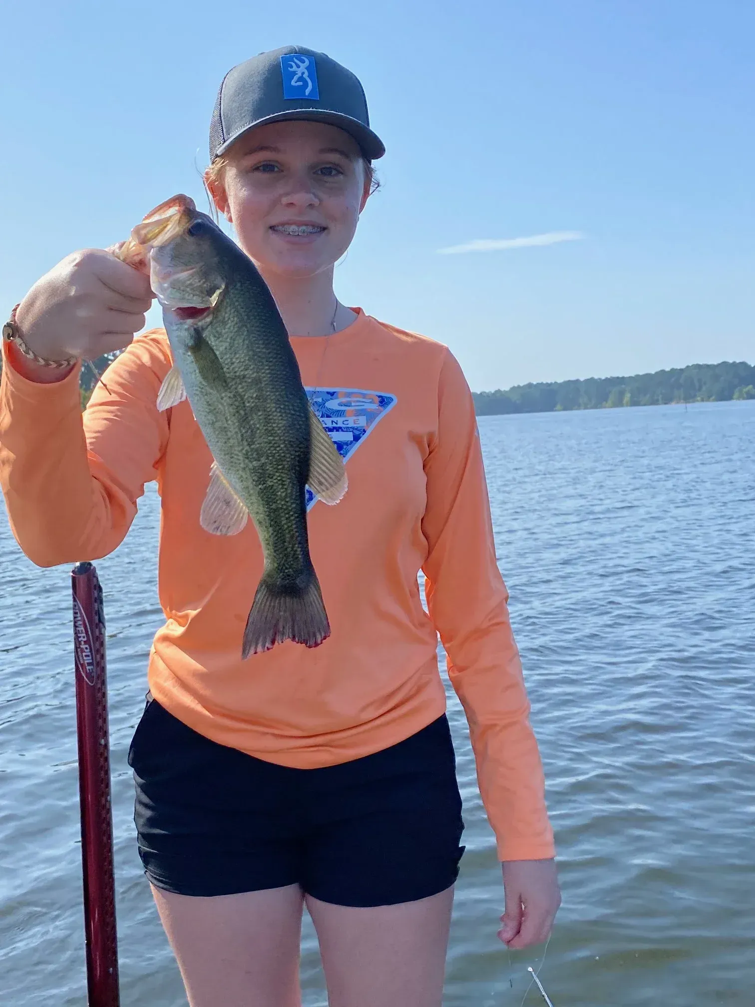 a woman in an orange shirt is holding a fish in her hands .