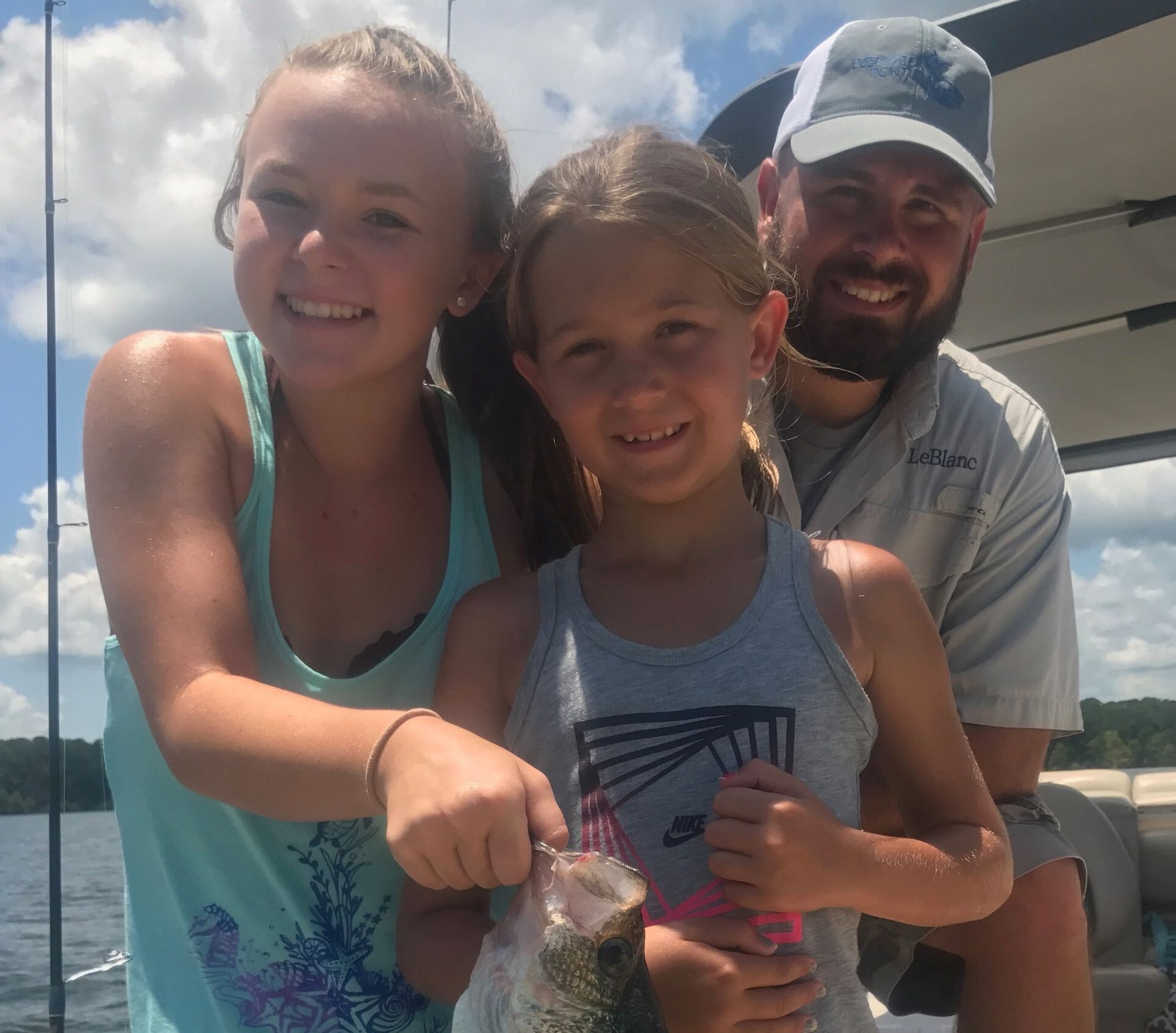 a man and two girls are holding a fish on a boat .