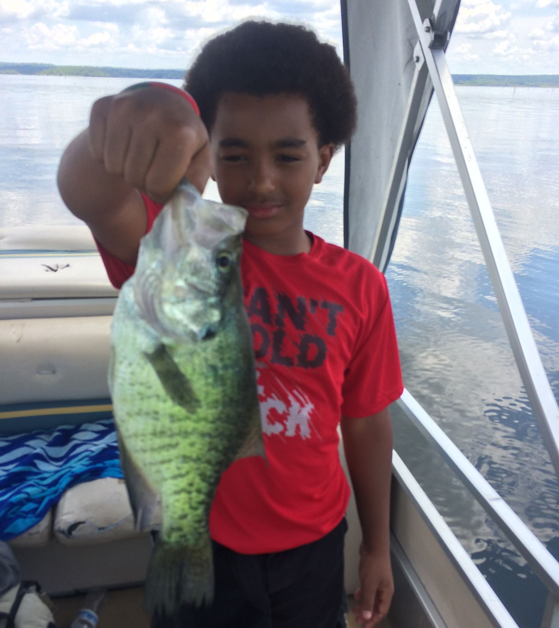 a boy in a red shirt holding a fish