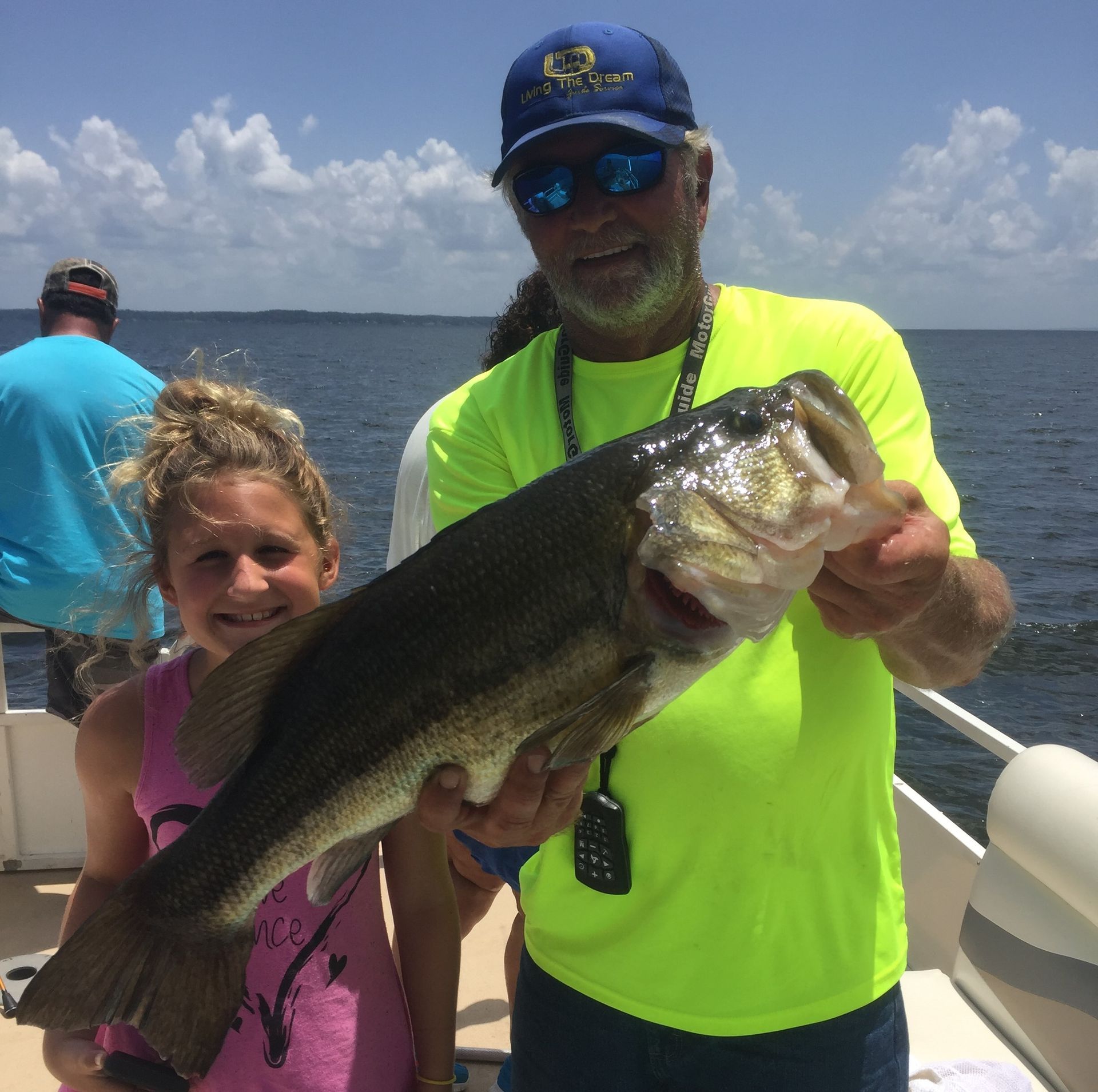 a man in a neon yellow shirt is holding a large fish