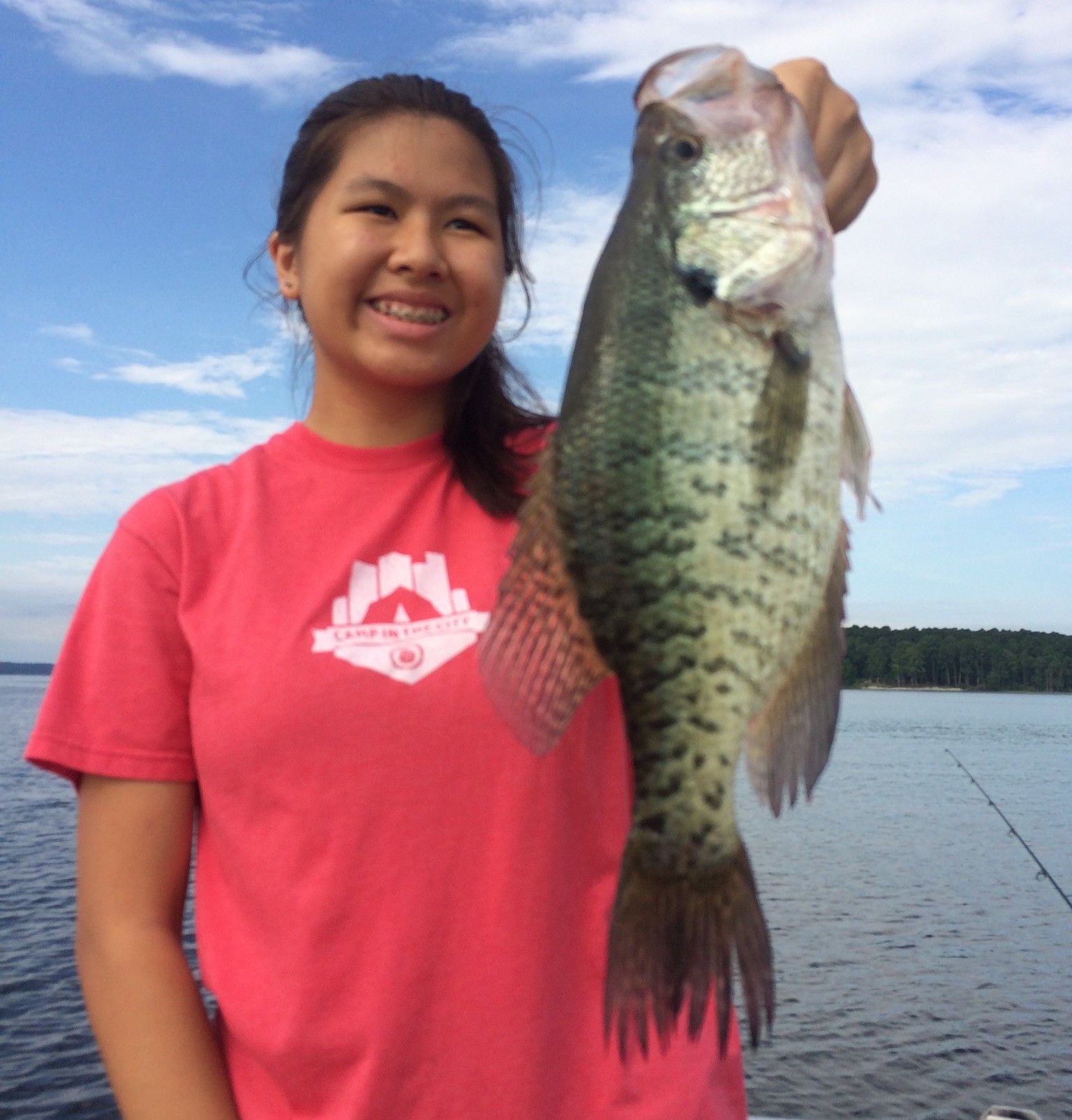 a woman in a pink shirt is holding a large fish