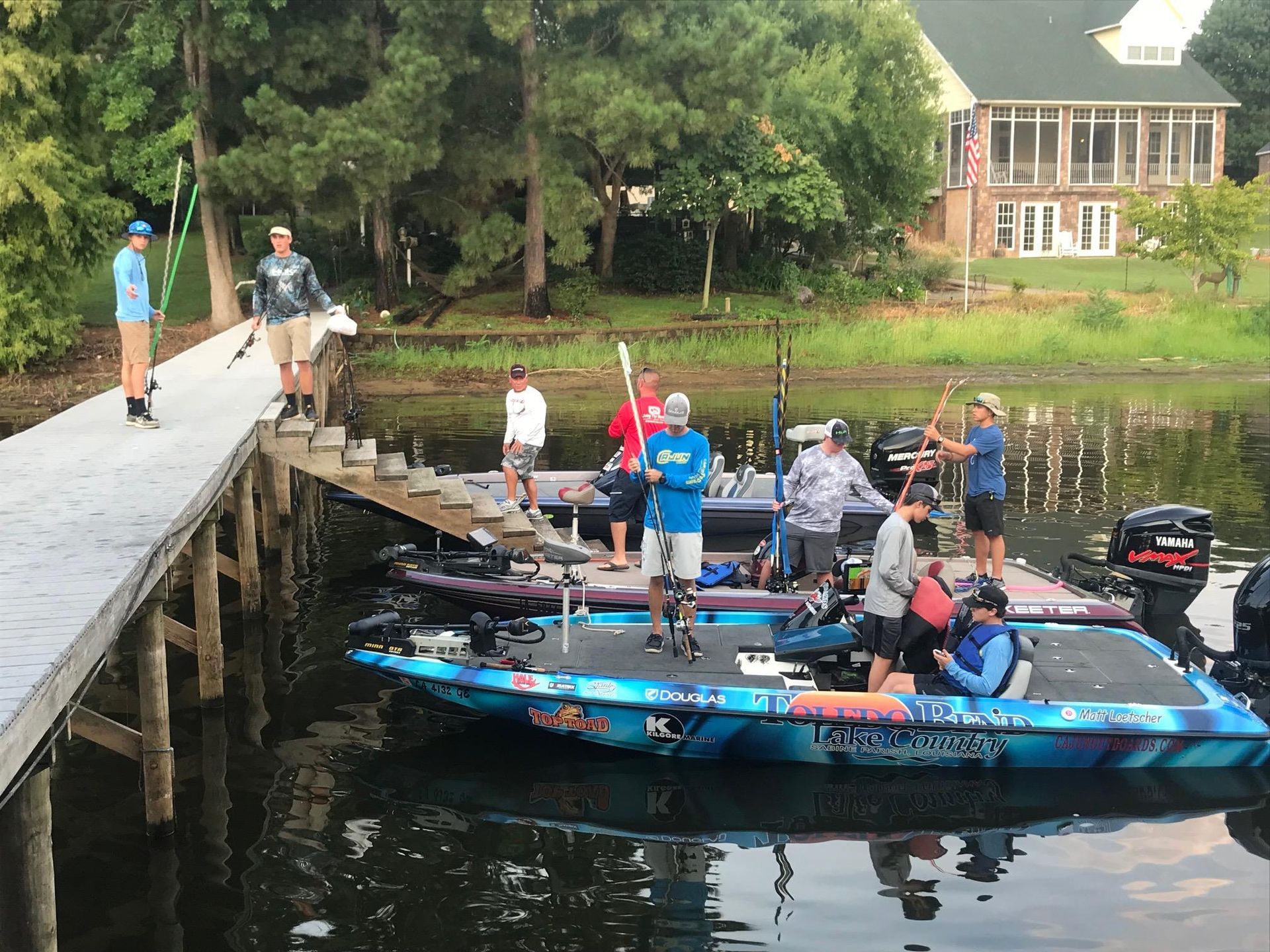 a group of people are standing on a dock next to boats on a lake .