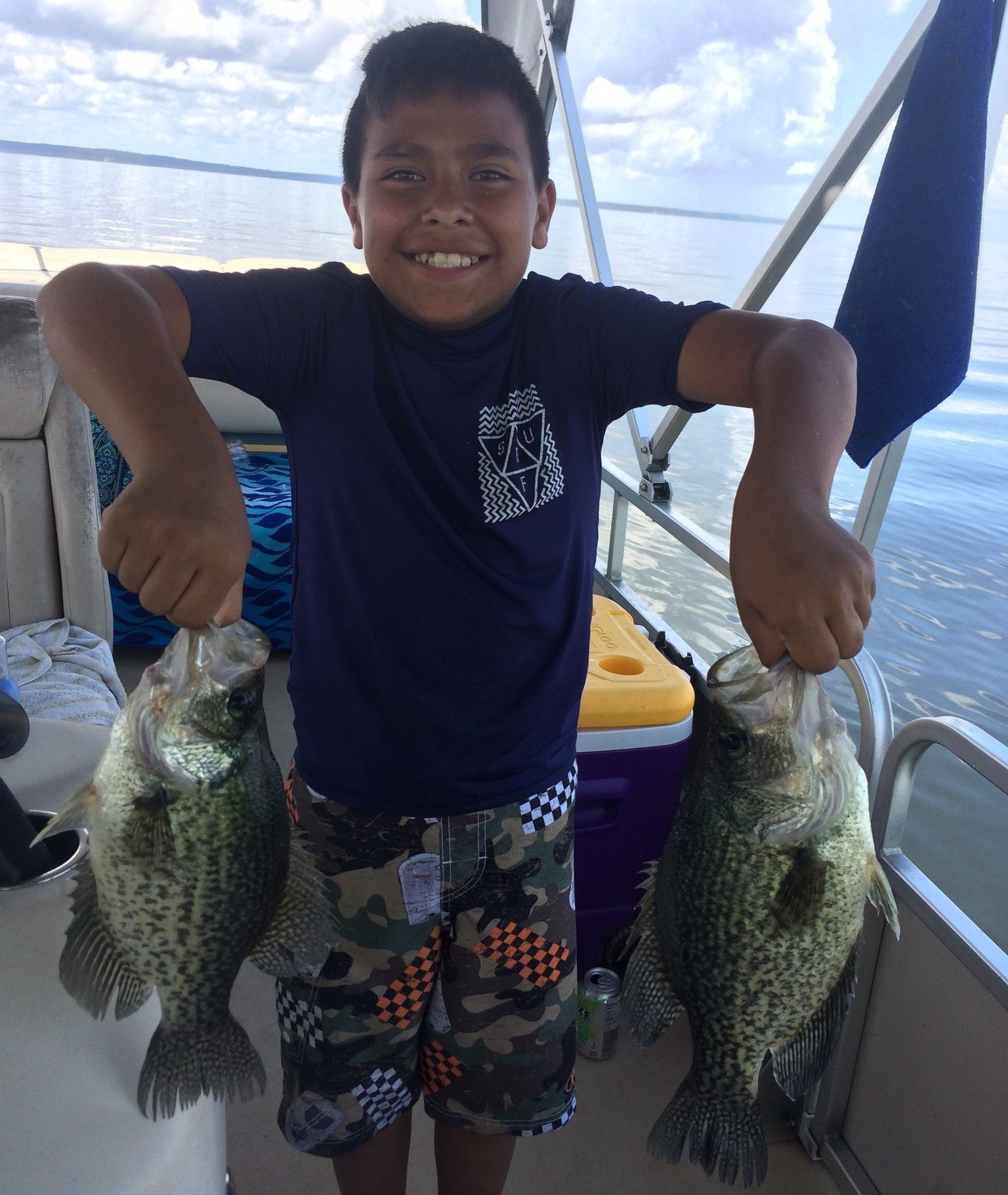 a young boy is holding two fish in his hands on a boat