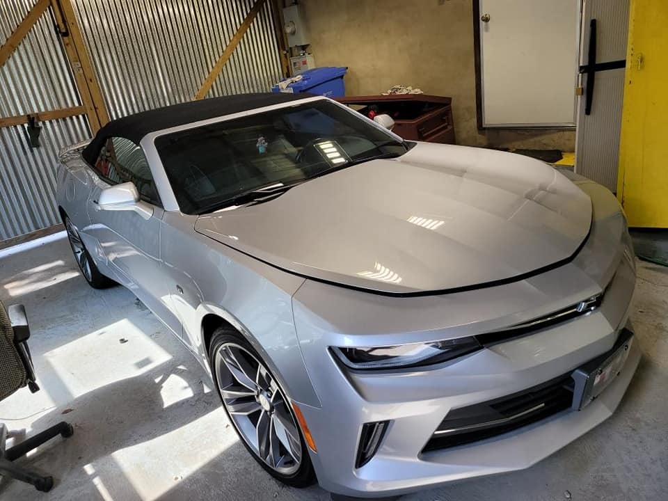 A silver convertible car is parked in a garage.