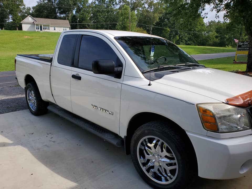 A white truck is parked in a driveway next to a grassy hill.