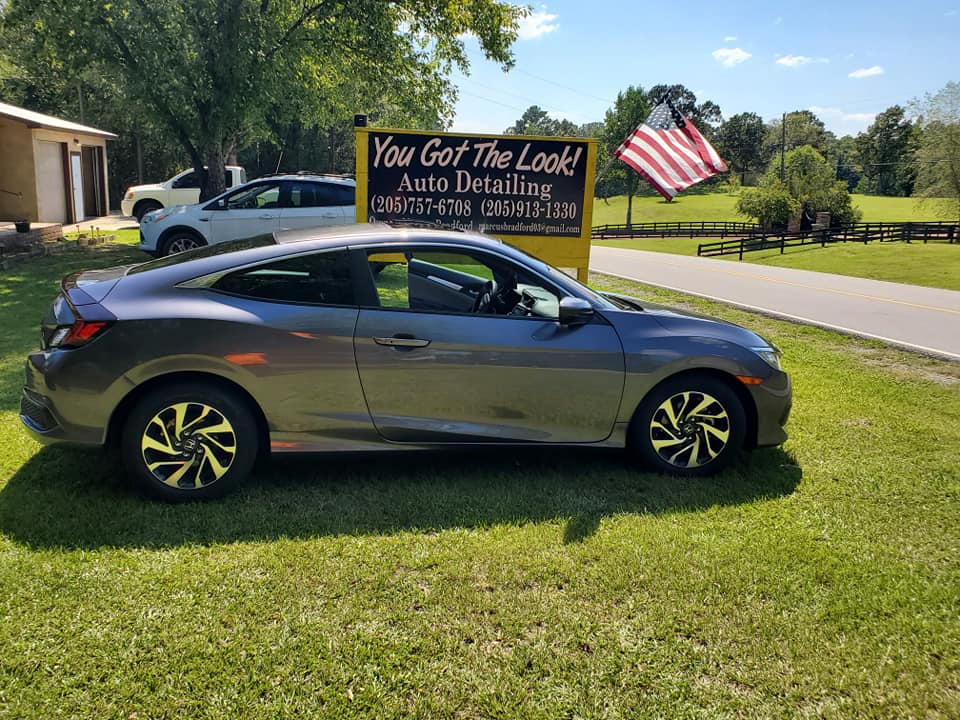 A car is parked in front of a sign that says `` you got the look ''.