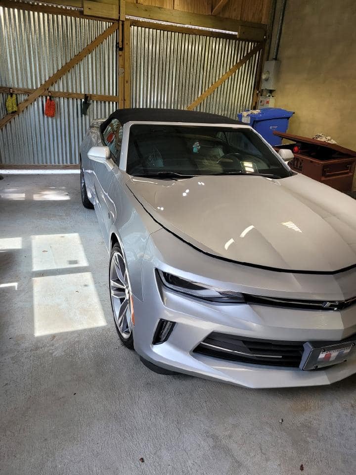 A silver convertible car is parked in a garage.
