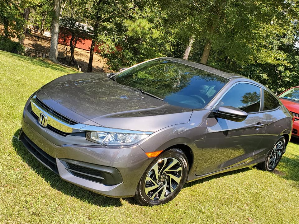 A gray honda civic coupe is parked in the grass.