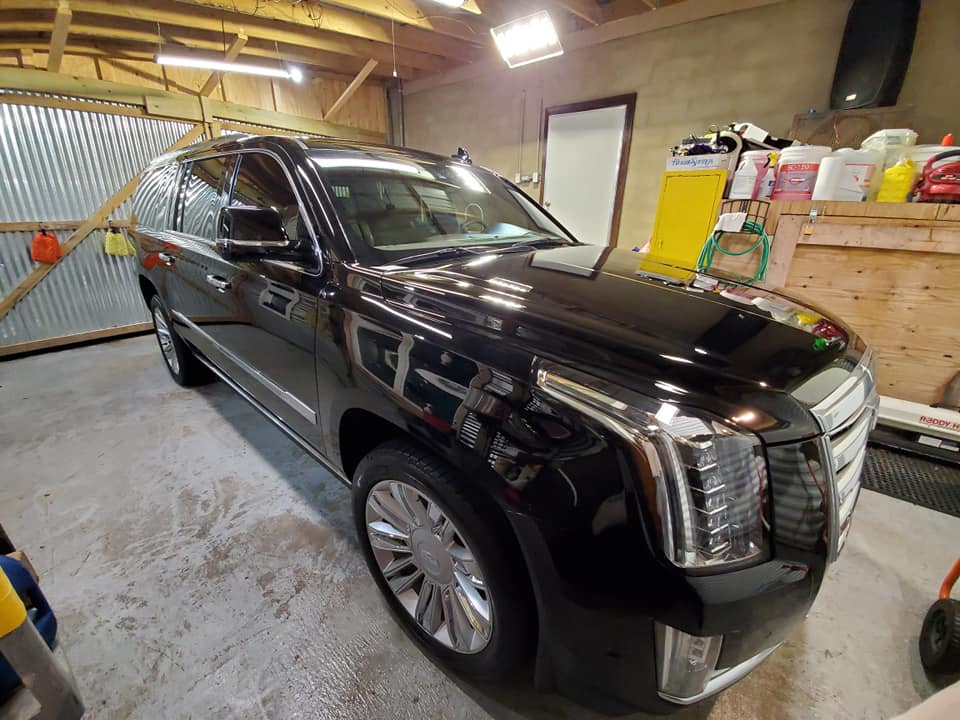 A black cadillac escalade is parked in a garage.