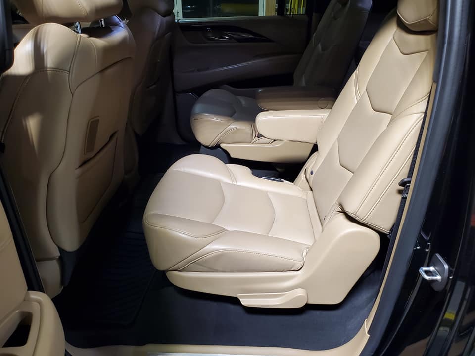 The back seat of a black car with tan leather seats