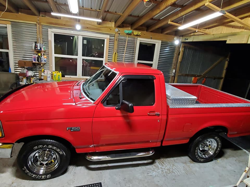 A red pickup truck is parked in a garage.