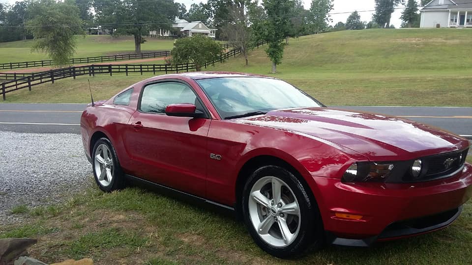 A red mustang is parked on the side of the road